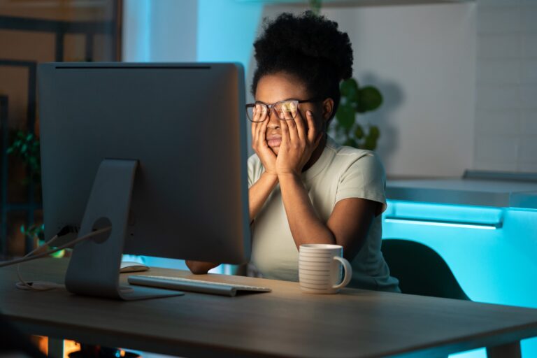 Overworked african woman freelancer feeling eye strain and fatigue during prolonged computer use