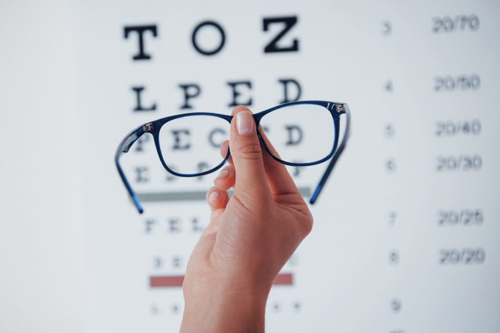 Woman hand holding the glasses on background of the eye chart